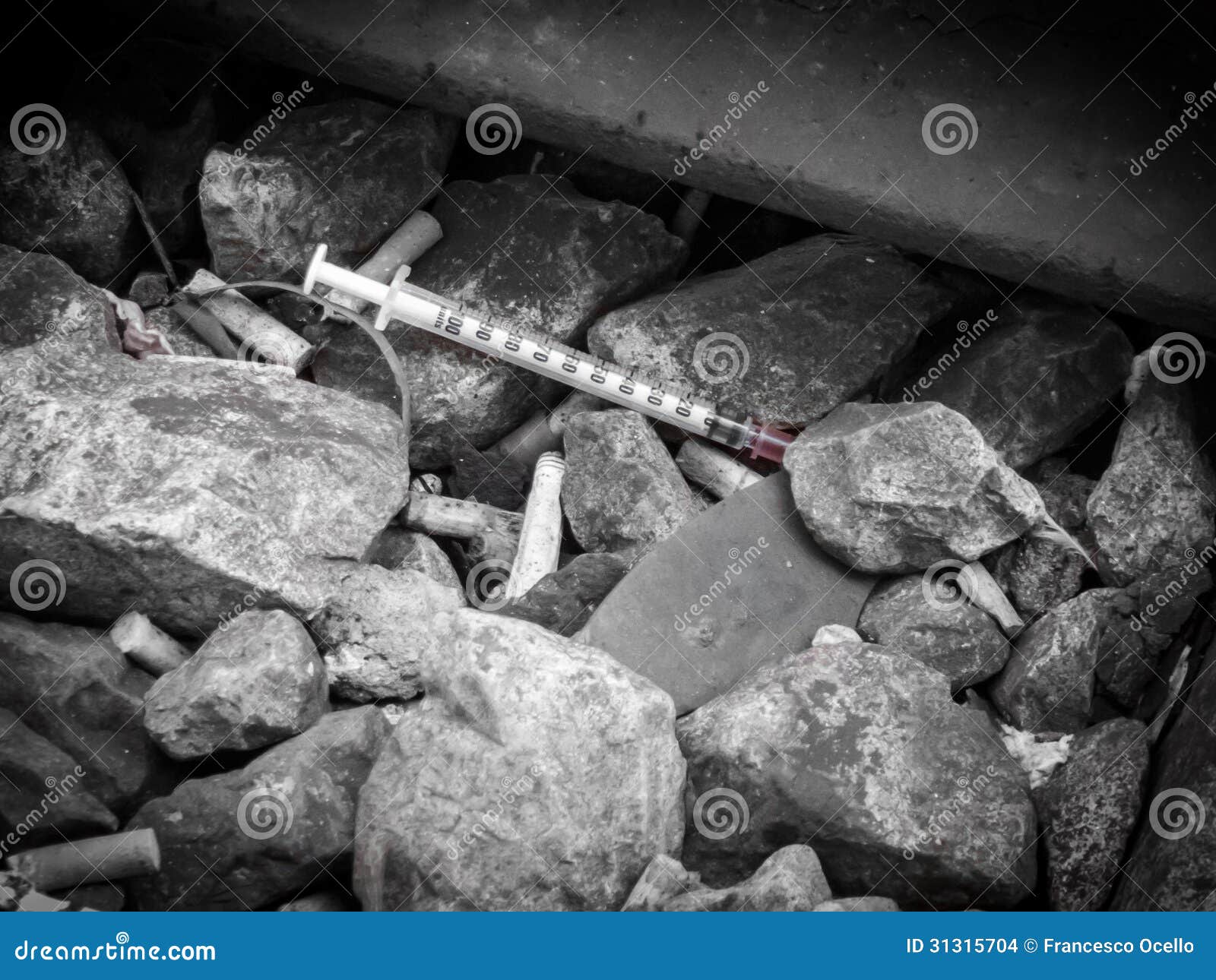 discarded syringe lying amongst stones