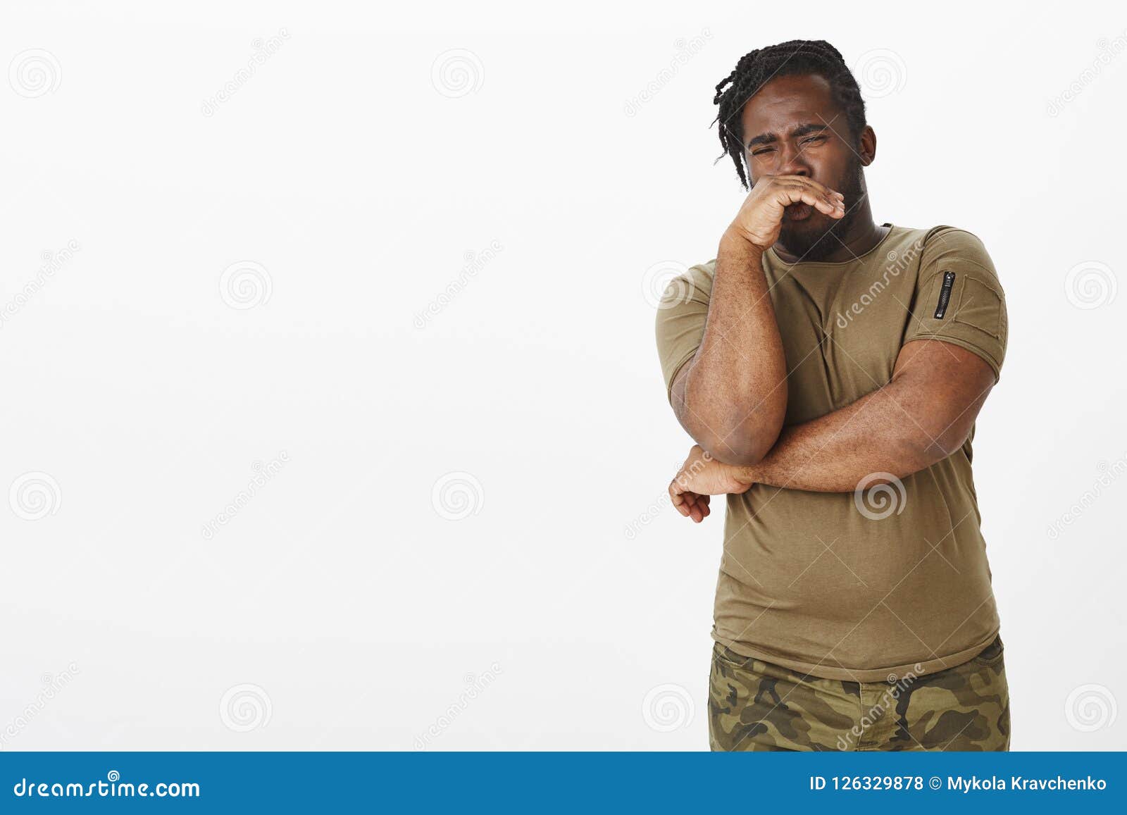 disgusted unhappy dark-skinned man in military outfit, covering nose with palm from reek or awful smell, expressing