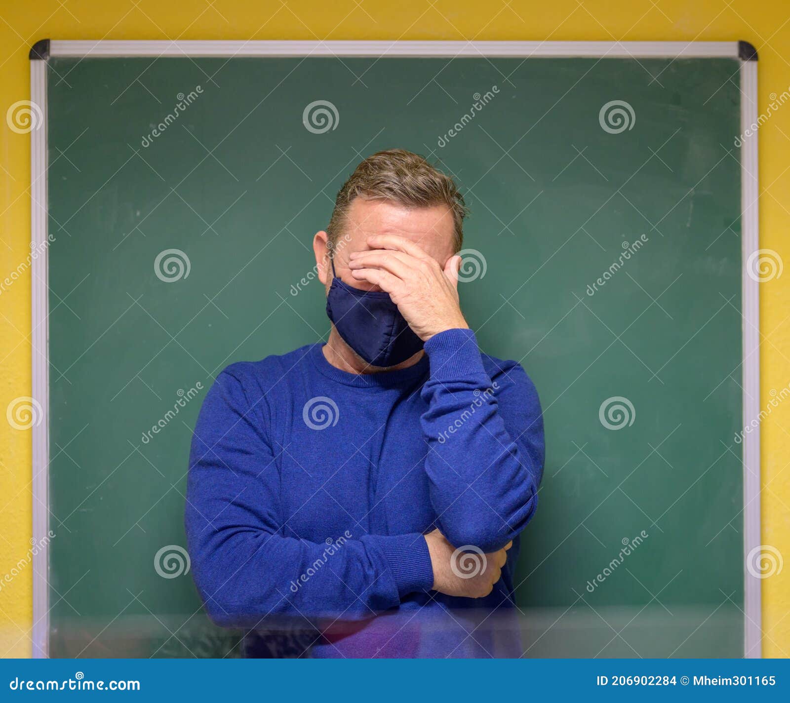 dismayed male teacher holding his head in his hand