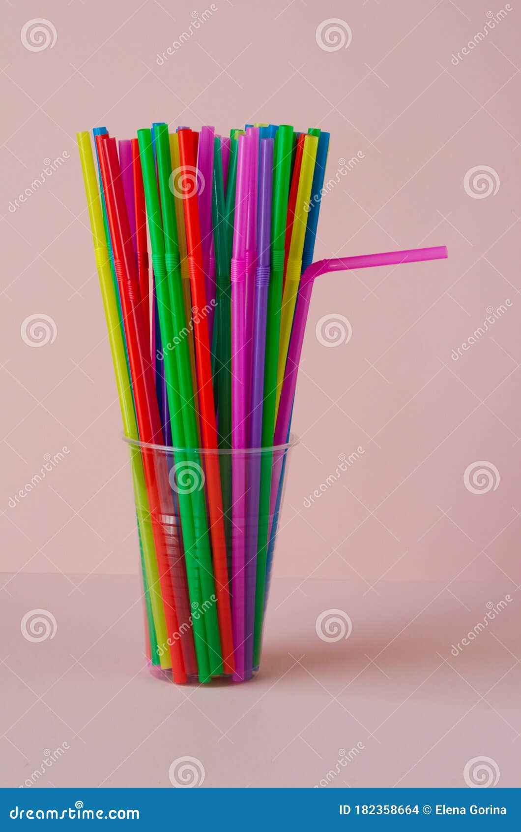 Disposable Plastic Colored Straws in a Plastic Cup on a Pink Background