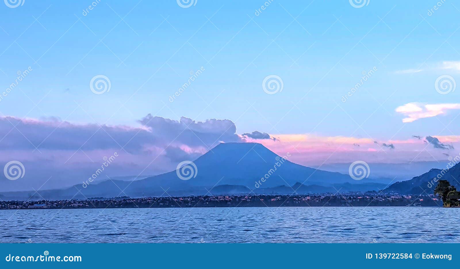 distant susnset view of nyiragongo mountain in democratic republic of congo, seen from lake kivu, rwanda.