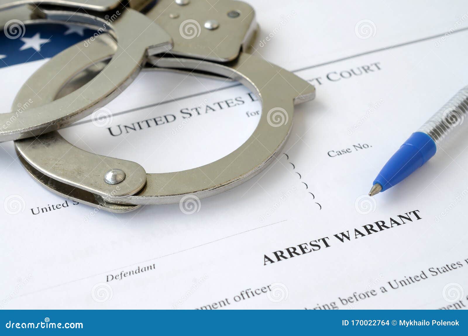 district court arrest warrant court papers with handcuffs and blue pen on united states flag. concept of permission to arrest