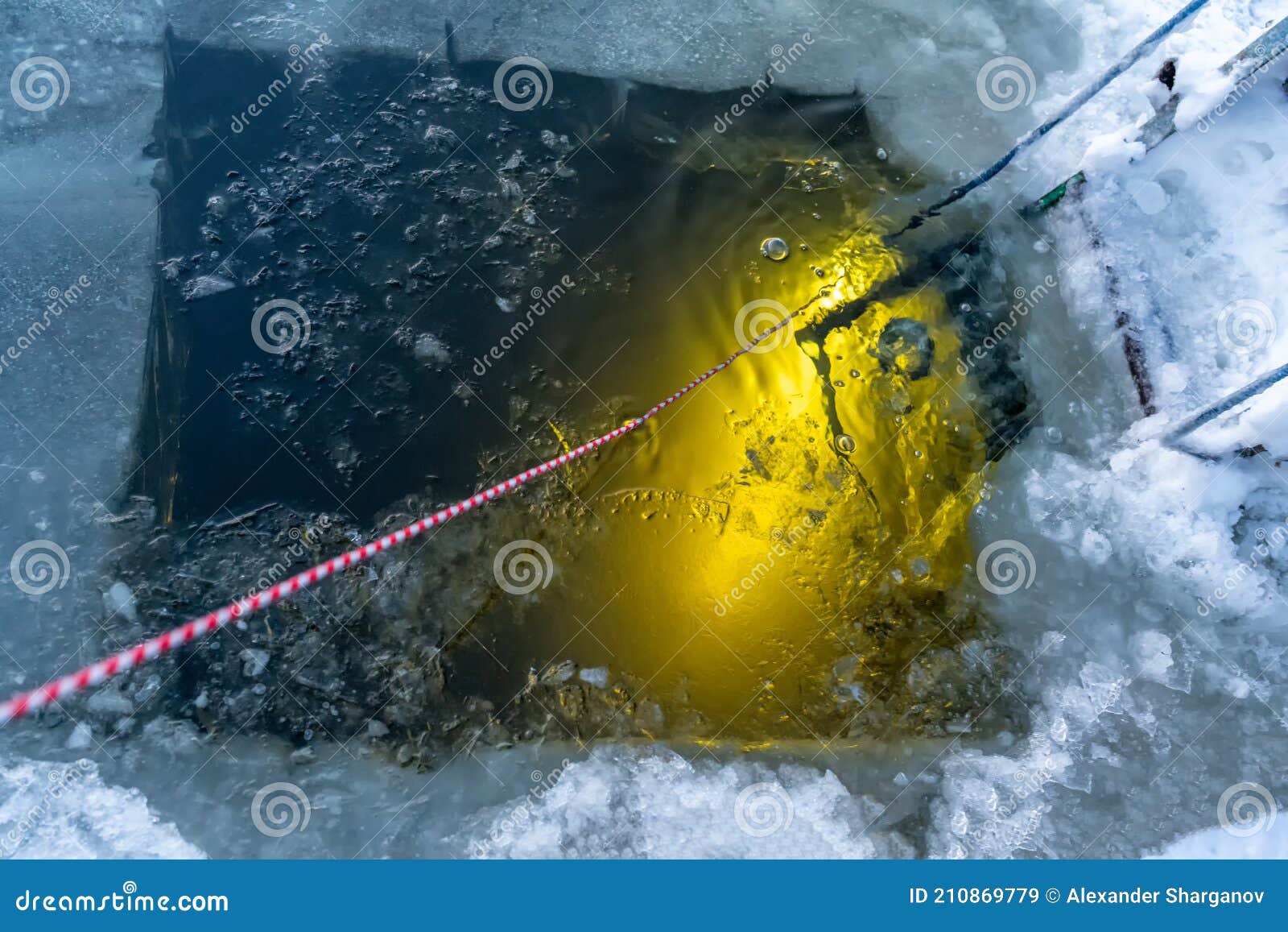 A Diver from Under the Water Shines with a Flashlight Torch an Ice Hole