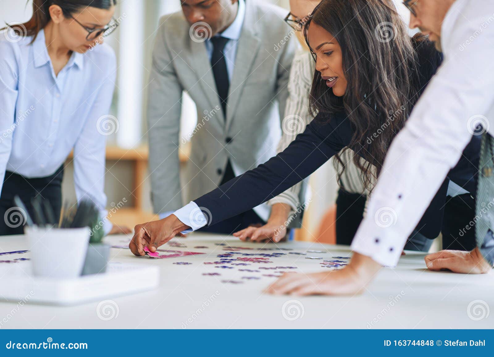 diverse businesspeople standing in a boardroom solving a jigsaw