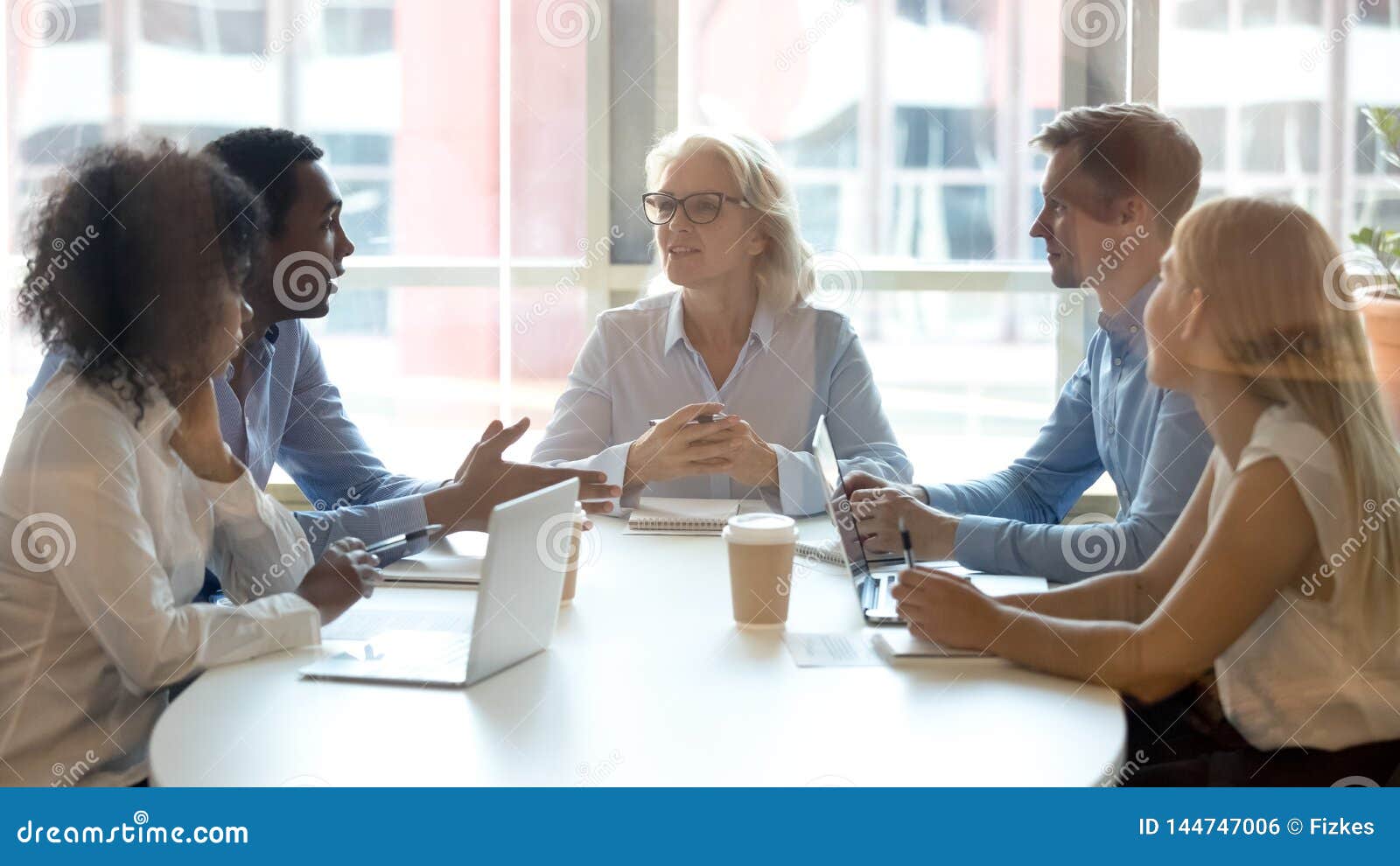 multicultural professional team colleagues having conversation sit at conference table