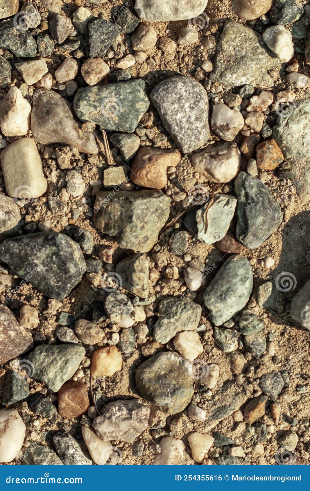 diverse collection of small rocks and pebbles on dry, sandy ground