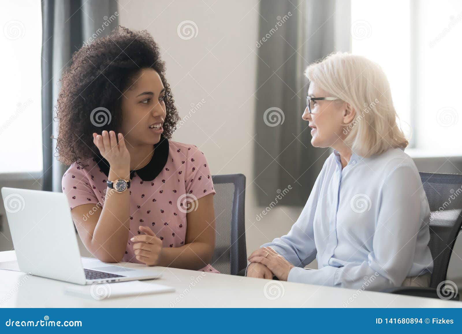 diverse old and young female colleagues talking at work