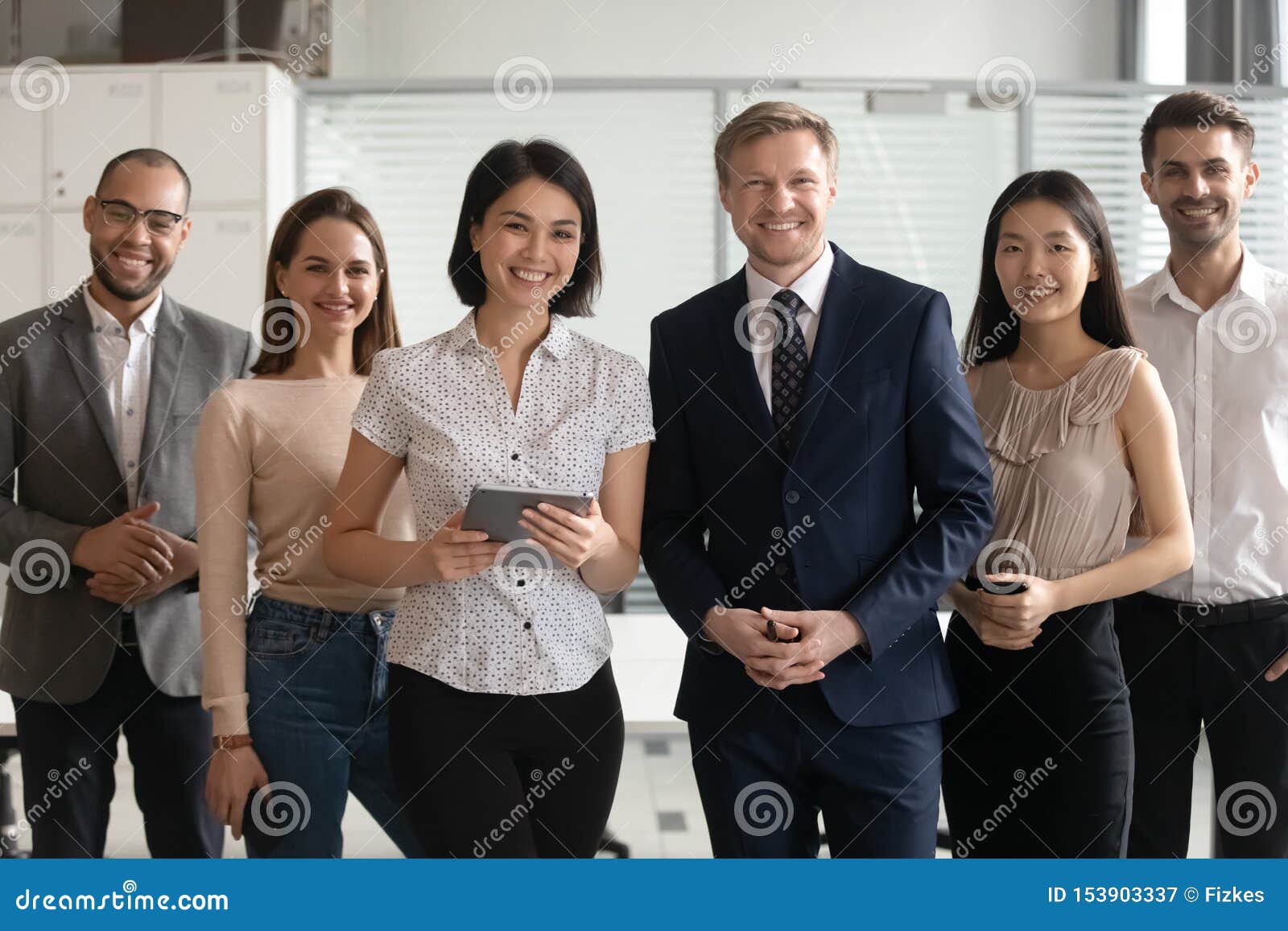 diverse professional business leaders posing with multicultural workers in office