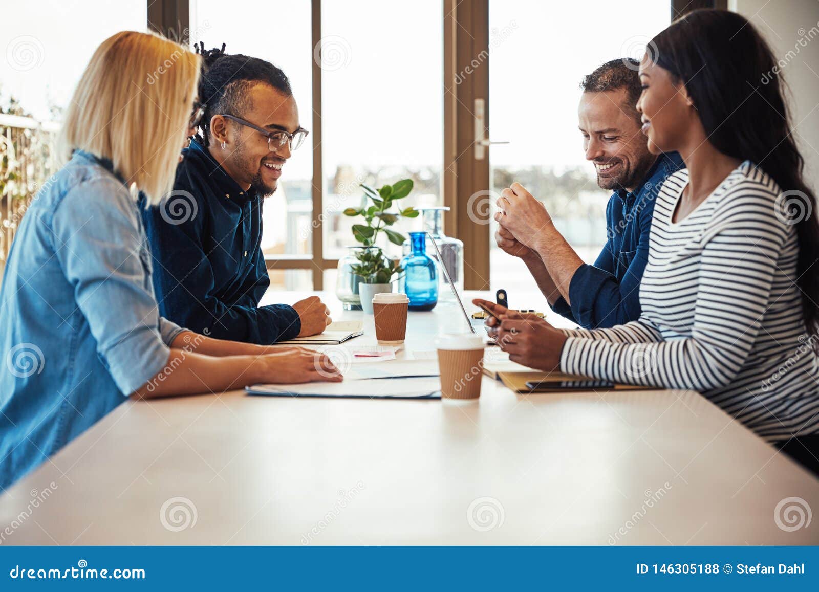 group of laughing coworkers high fiving during an office meeting