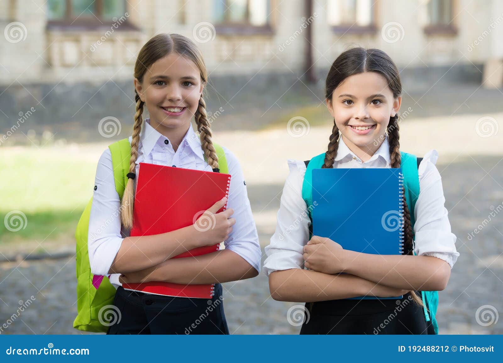 Dos niñas sonrientes con mochilas escolares. Las alumnas de 7 y 10 años  hablando en la escuela. Niña escribe en un bloc de notas Fotografía de  stock - Alamy