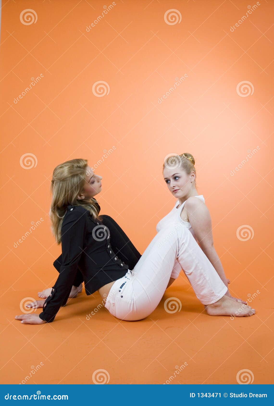 Divulgación de un secreto. Dos mujeres jovenes que se sientan en el suelo en direcciones opuestas, teniendo una conversación.