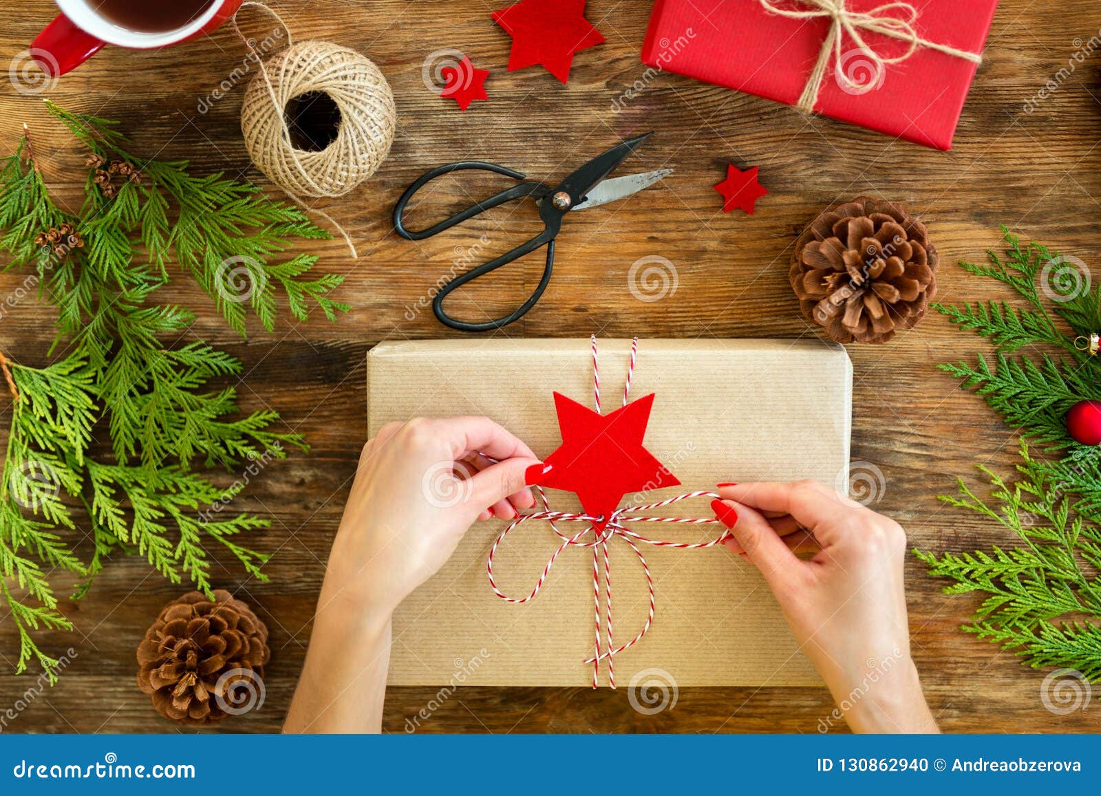 diy gift wrapping. woman wrapping beautiful red christmas gifts on rustic wooden table. overhead view christmas wrapping.