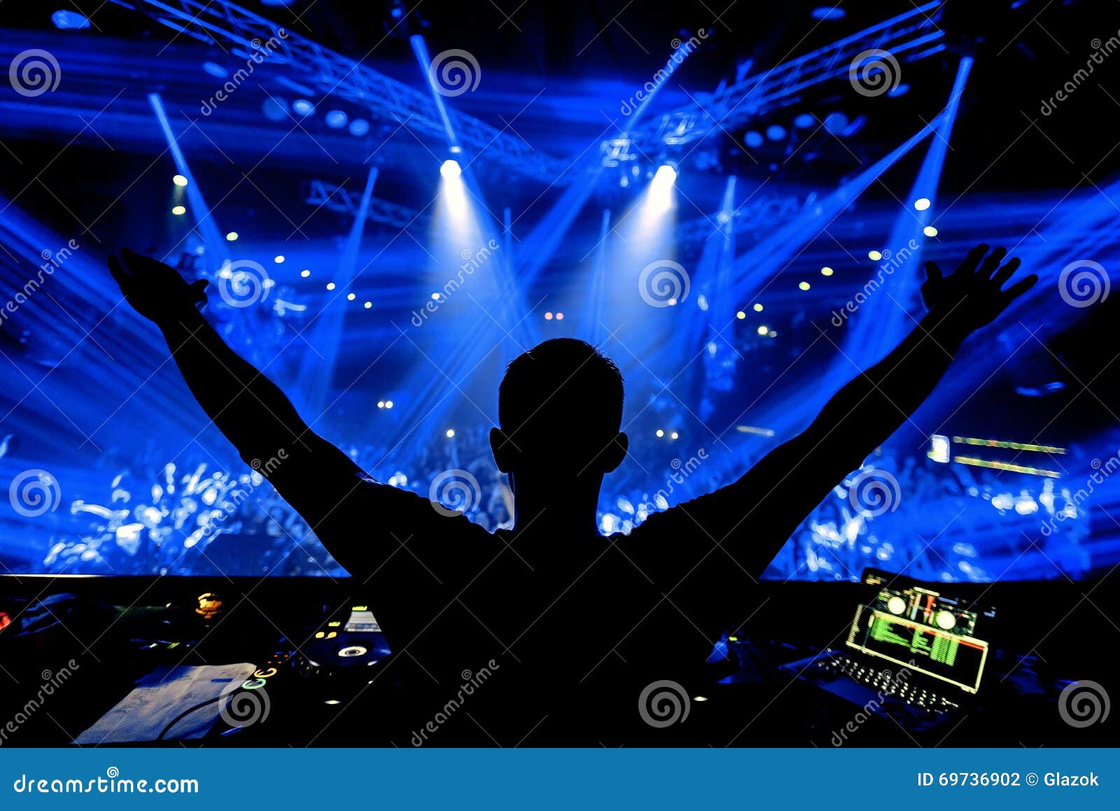 dj hands up at night club party under blue light with crowd of people