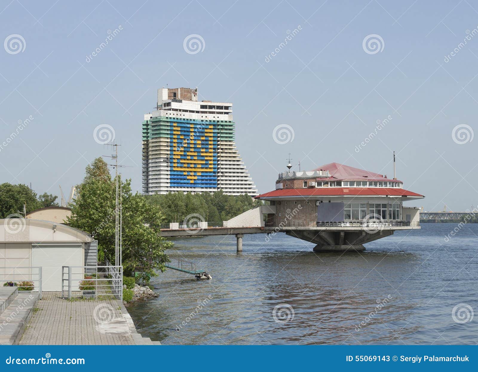 Dnipropetrovsk cityscape with Dnieper river, Ukraine. Dnipropetrovsk cityscape with Dnieper river and coat of arms of Ukraine performed on the facade of the unfinished hotel building, Ukraine