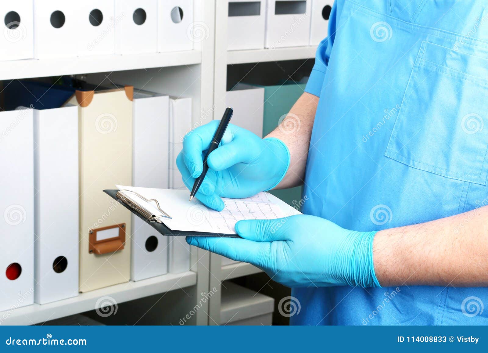 doctor in a blue uniforme write to the blank on a background of a shelf with folders.