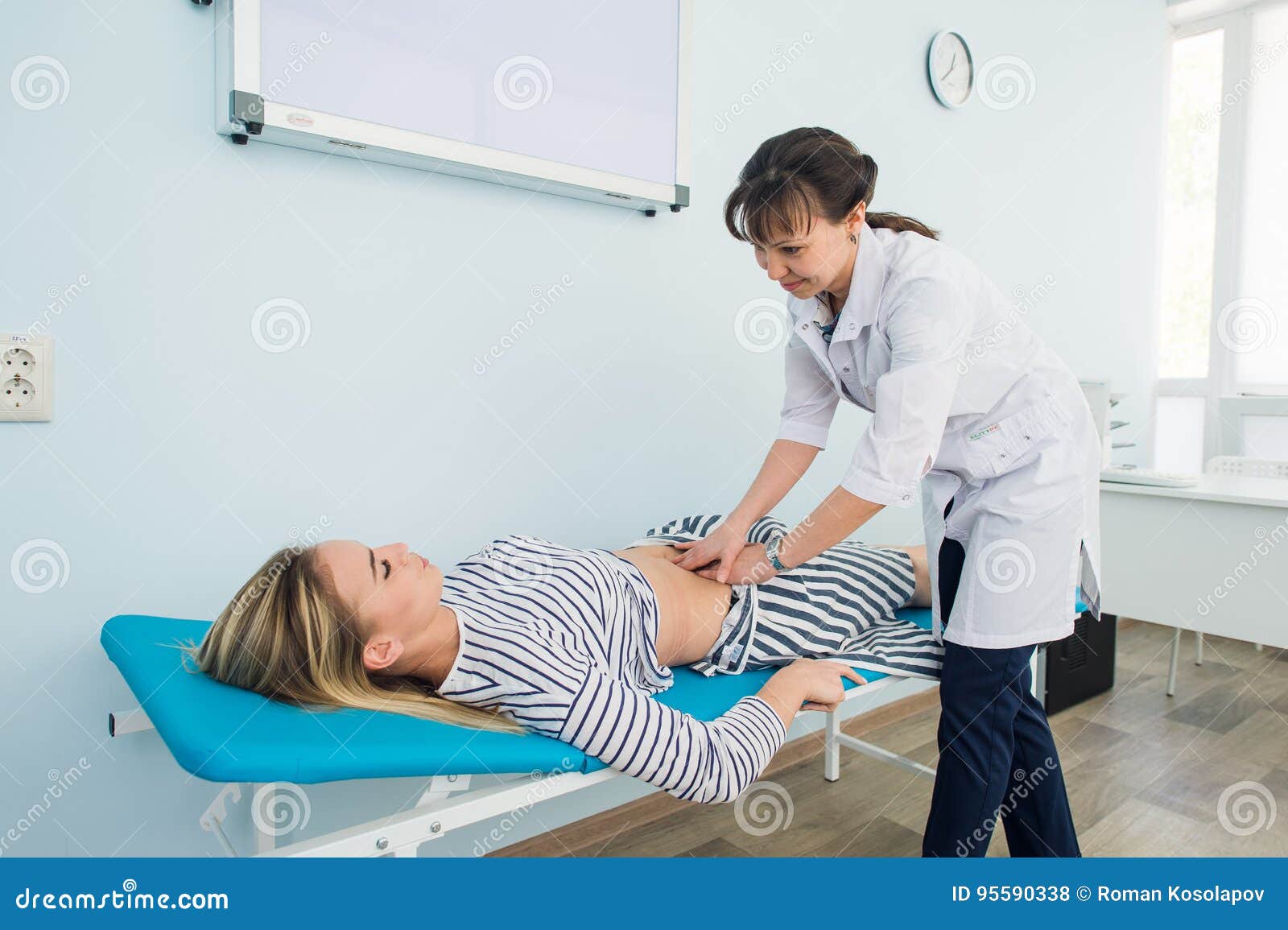 Doctor Checking the Stomach of One of Her Patients Stock Photo Image