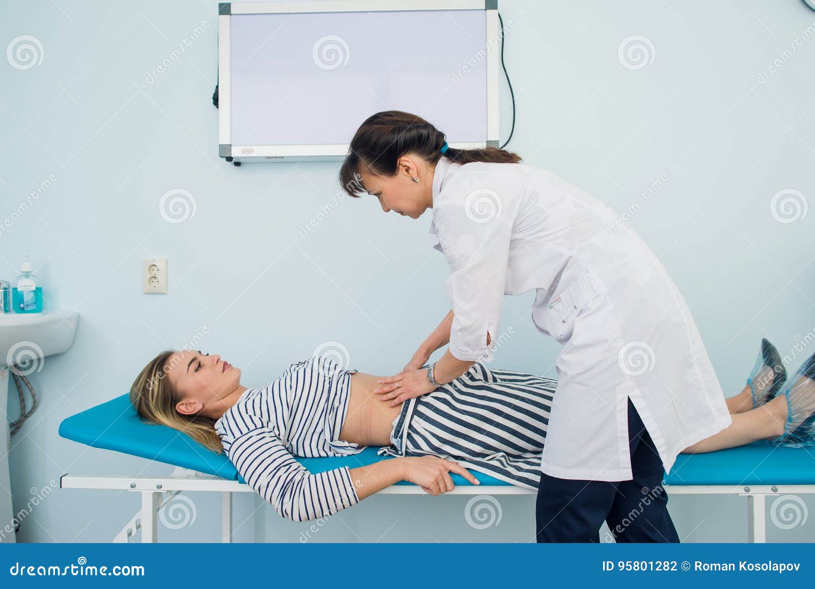 Doctor Checking the Stomach of One of Her Patients Stock Photo Image