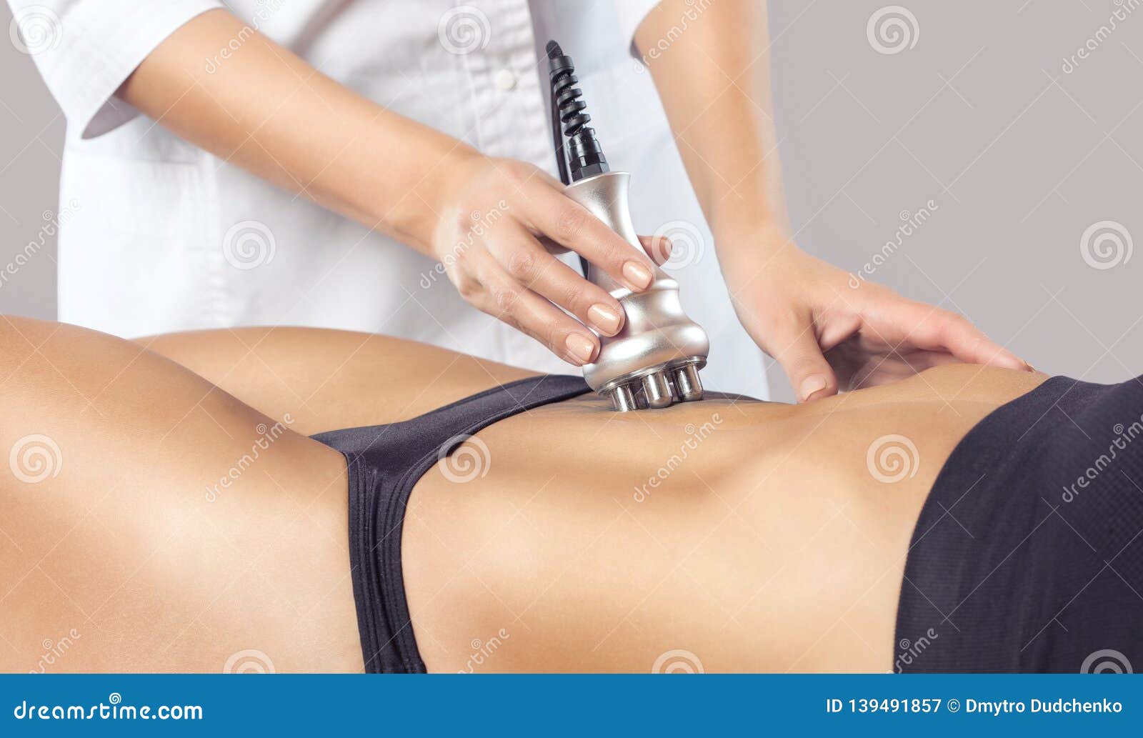 the doctor does the rf lifting procedure on the stomach and hips of a woman in a beauty parlor.