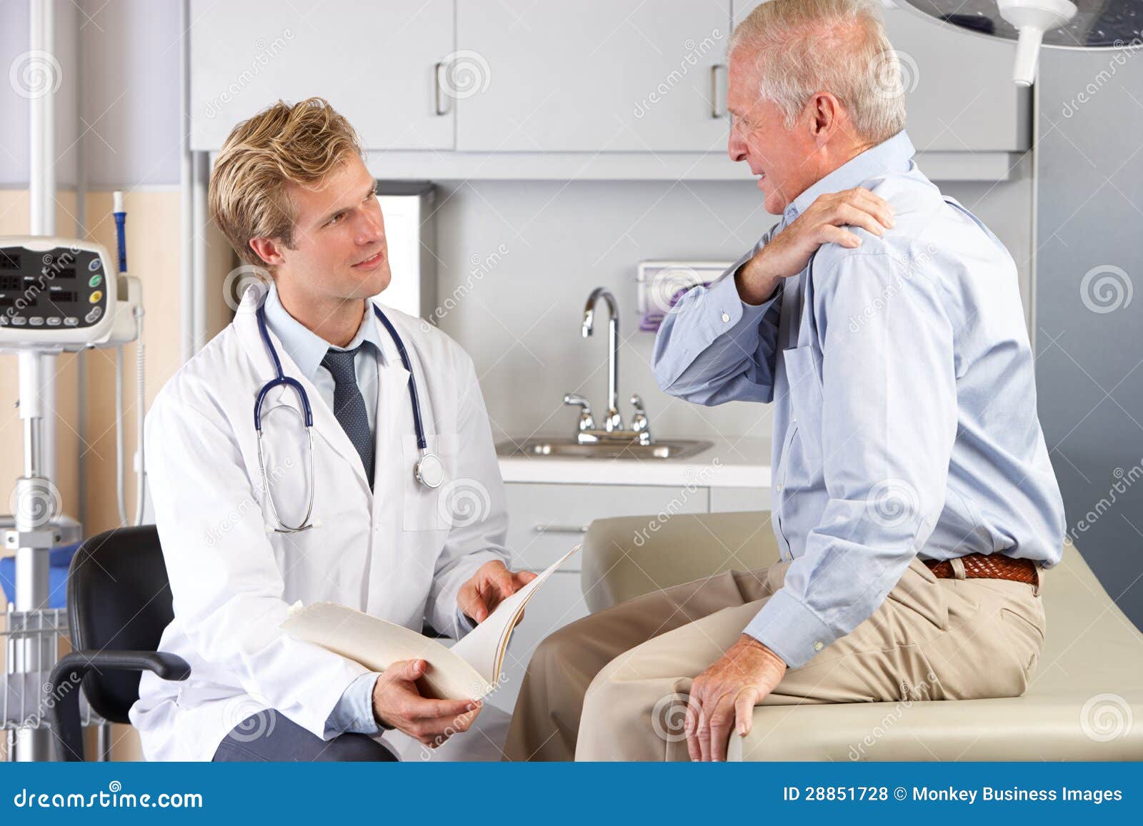 doctor examining male patient with shoulder pain