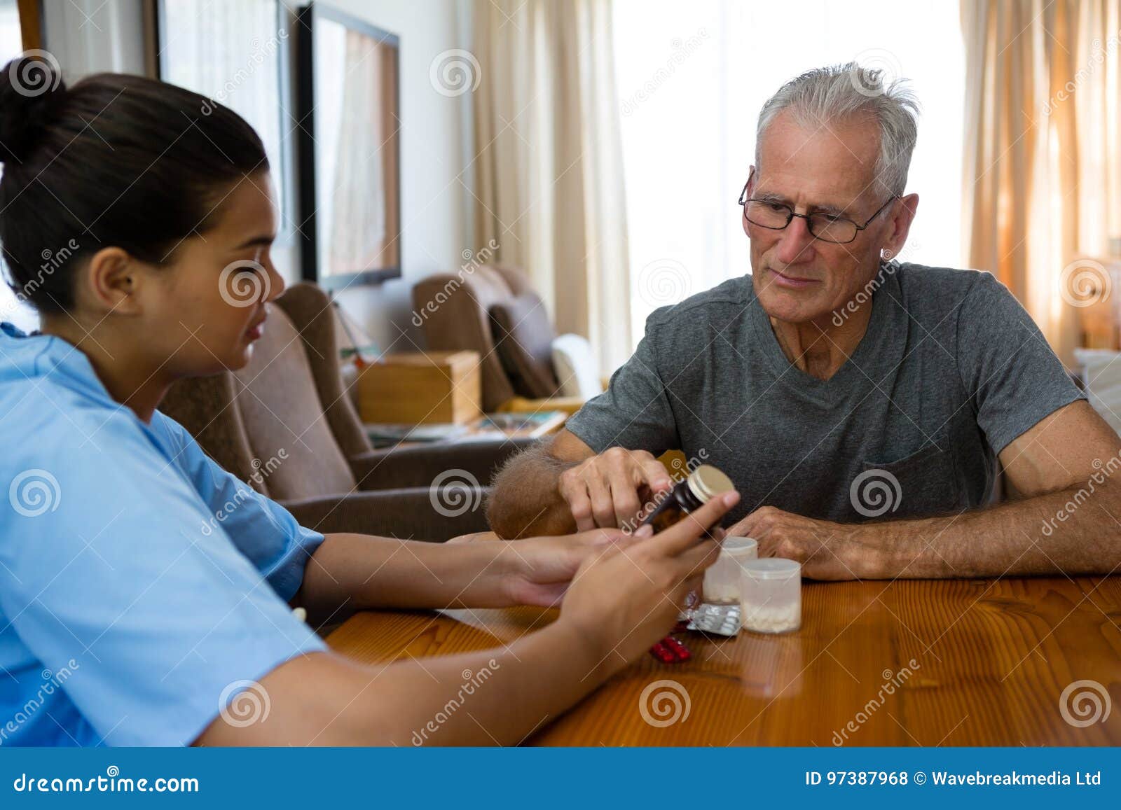 doctor guiding senior man in taking medicine at table