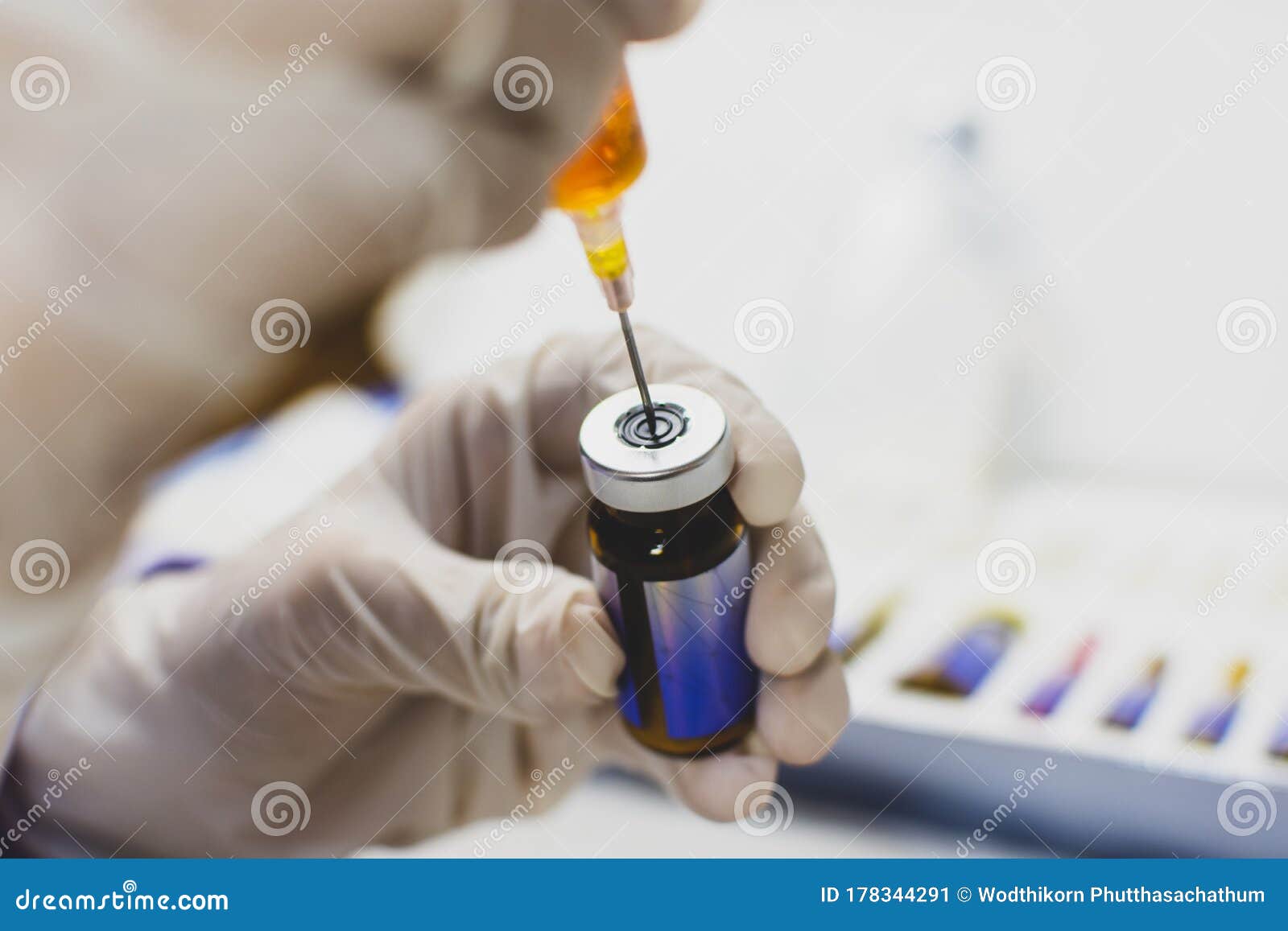 the doctor hand using syringe sucking medicine from drug vial bottle.