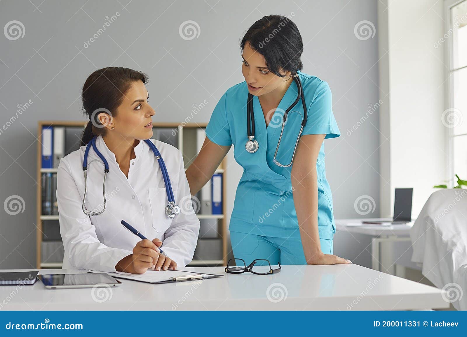 doctor and her assistant working together at hospital. physician and nurse with documents at medical office