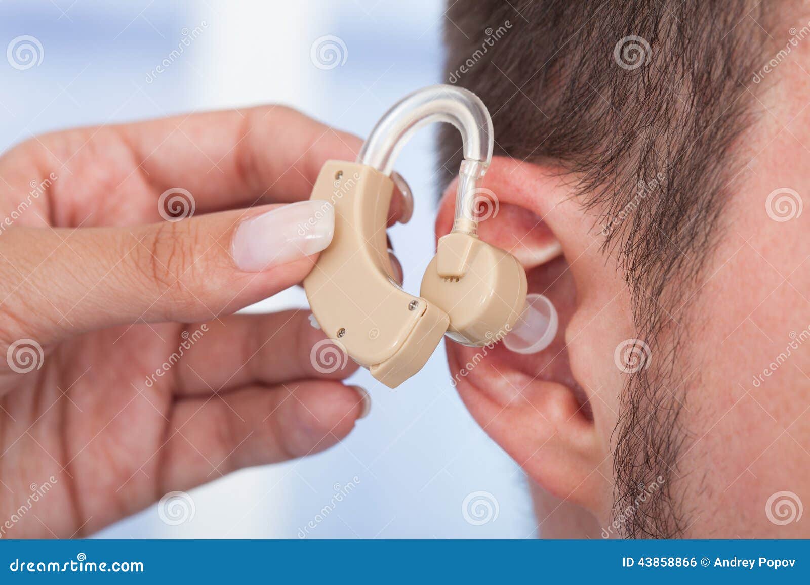 doctor inserting hearing aid in man's ear