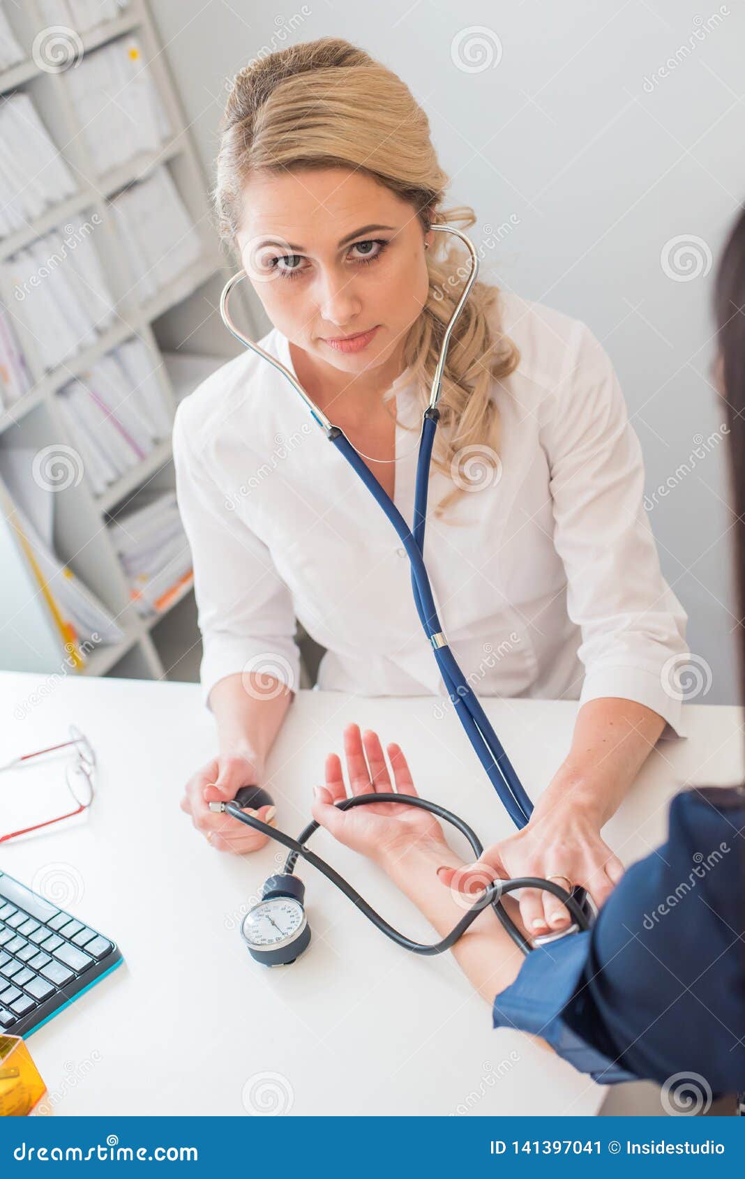 Female Nurse Measuring Blood Pressure Of Senior Woman At 