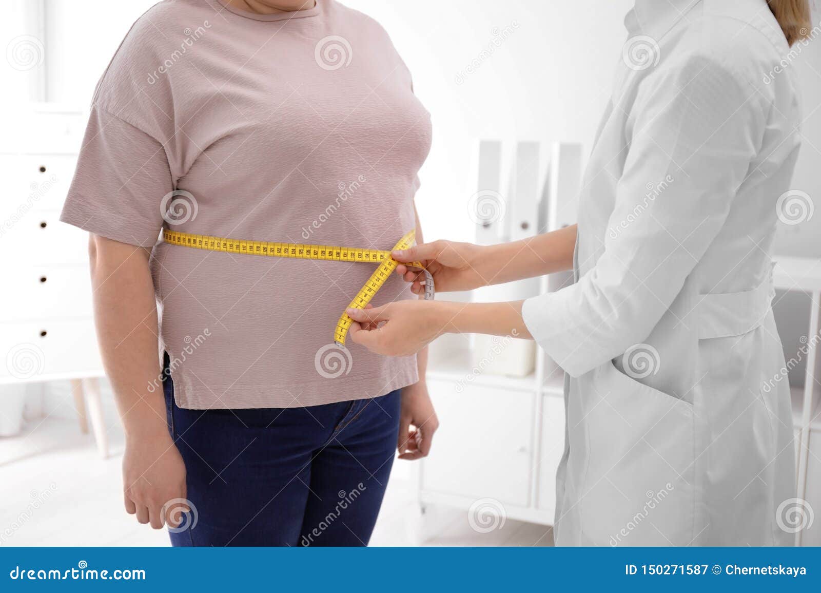 doctor measuring waist of overweight woman in clinic