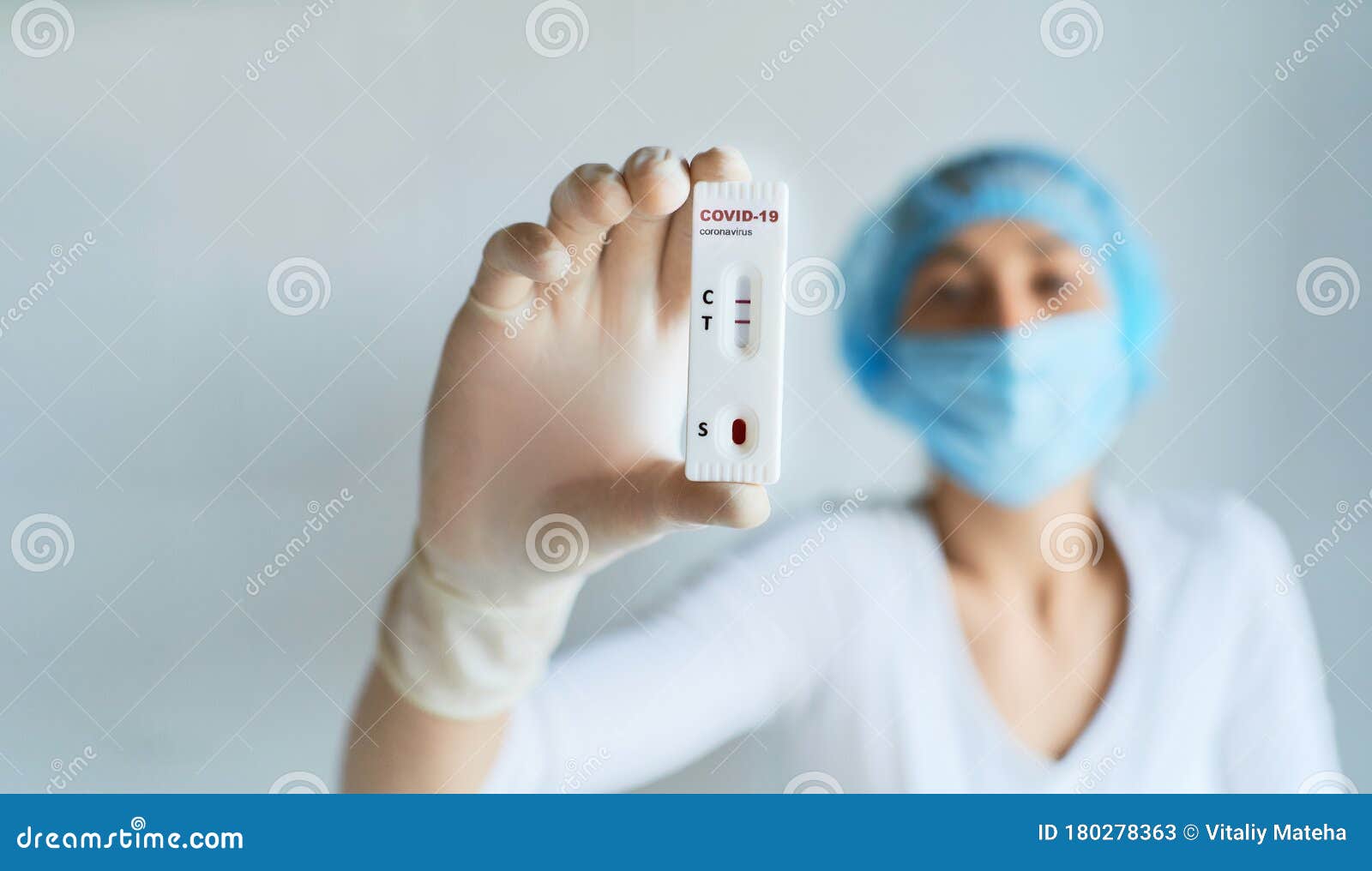 doctor or nurse in protective face and gloves holding in hand positive covid-19 rapid test.