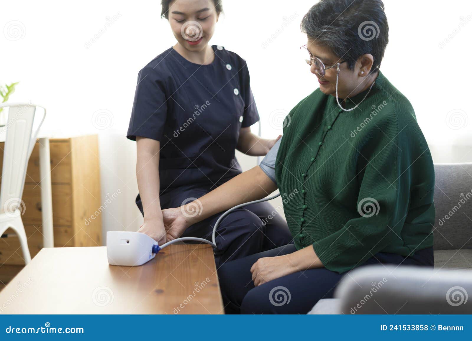 Doctor Or Nurse Using Blood Pressure Gauge With Old Women Patients At