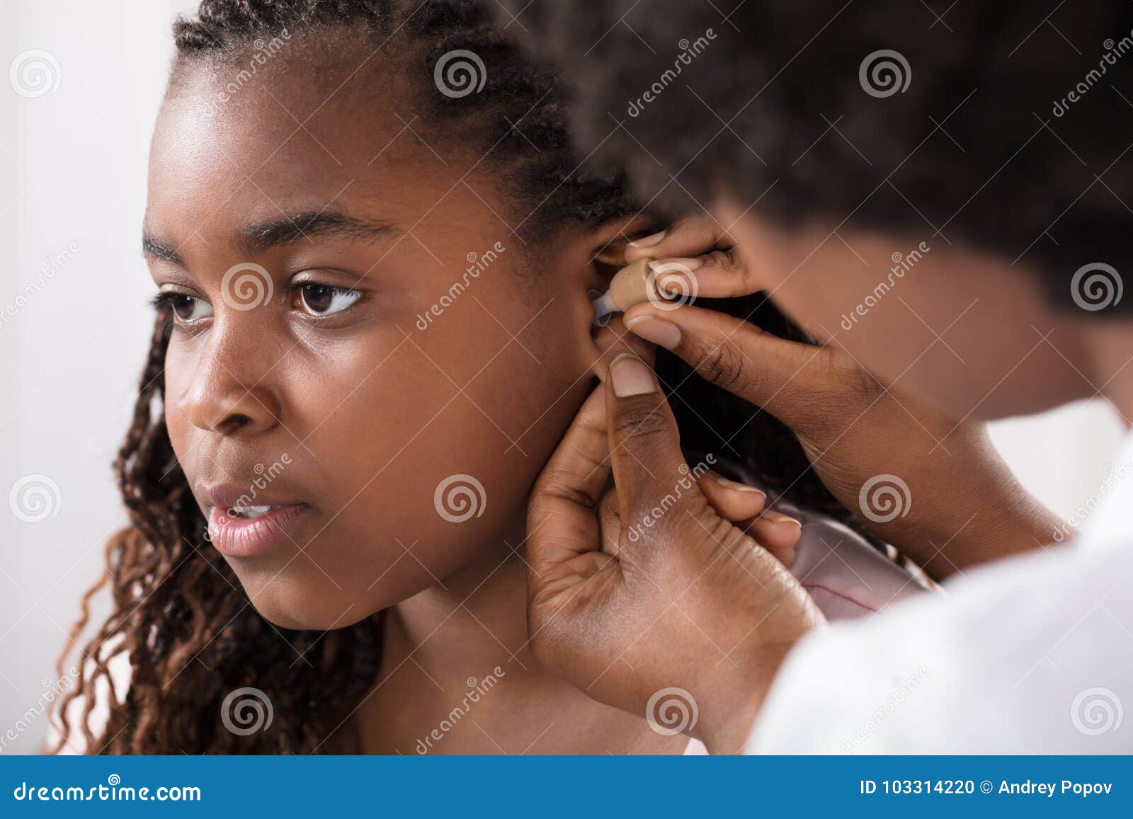 doctor putting hearing aid in patient`s ear