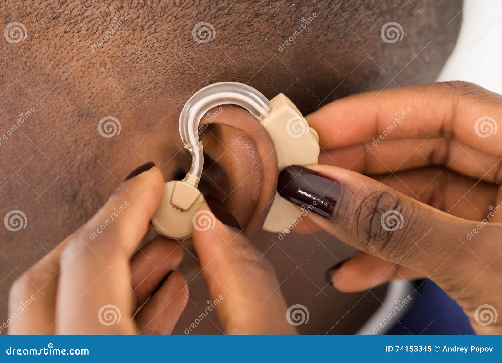 doctor's hand inserting a hearing aid into a man's ear