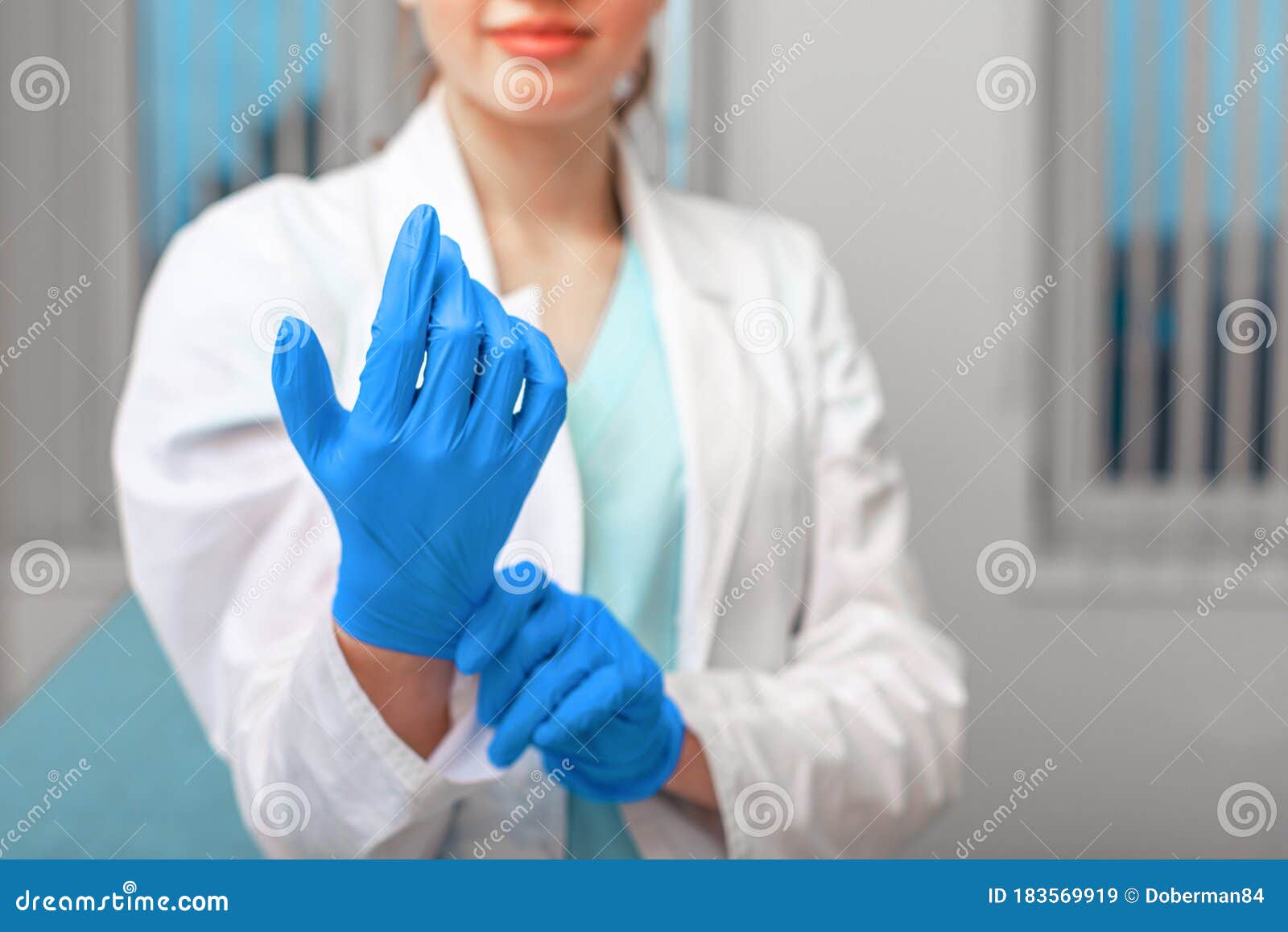 doctor`s hands putting on latex gloves in a hospital. woman in a doctor`s smock in latex gloves. protection against