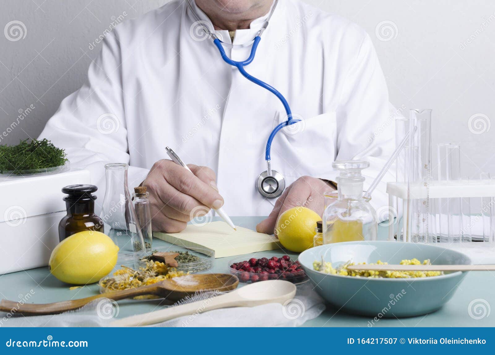 doctor sitting at the table. many ingredients for alternative medicine.dried berries,herbs,lemons and diffirent portions of natura
