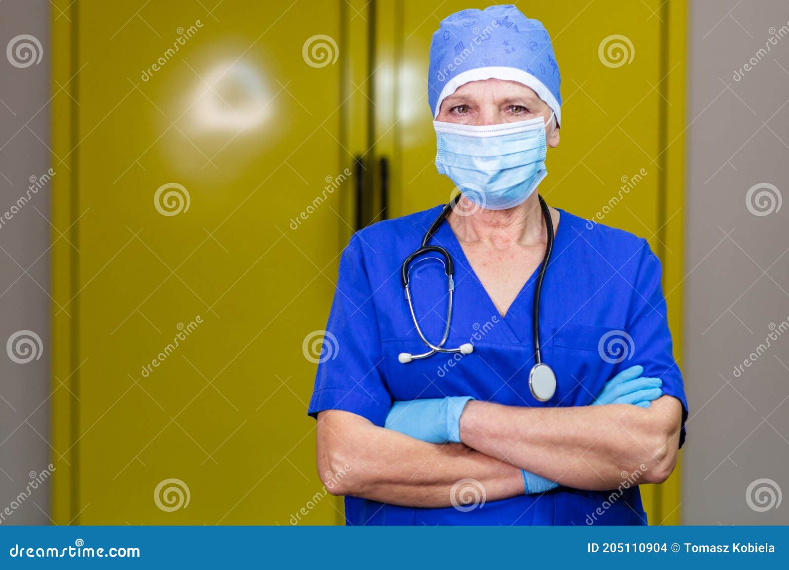 a doctor in surgical cap and stethoscope wearing nitrile gloves and a mask