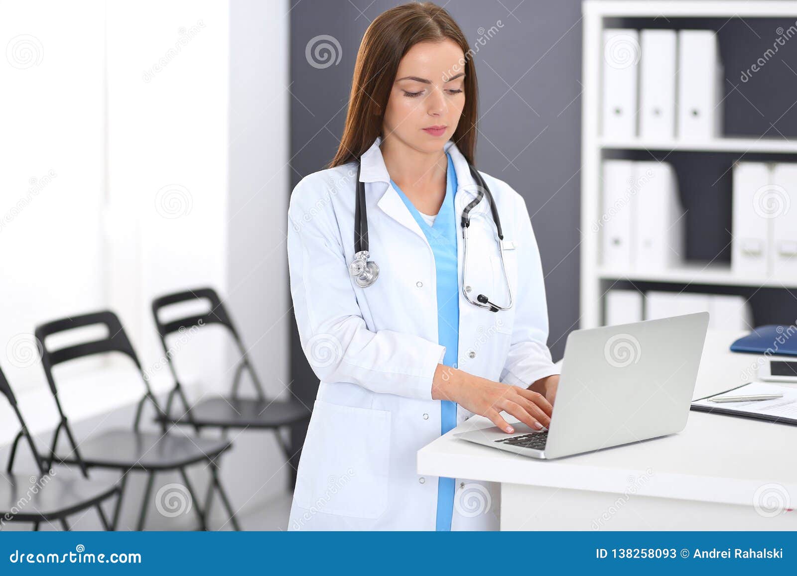 doctor woman at work. portrait of female physician using laptop computer while standing near reception desk at clinic or