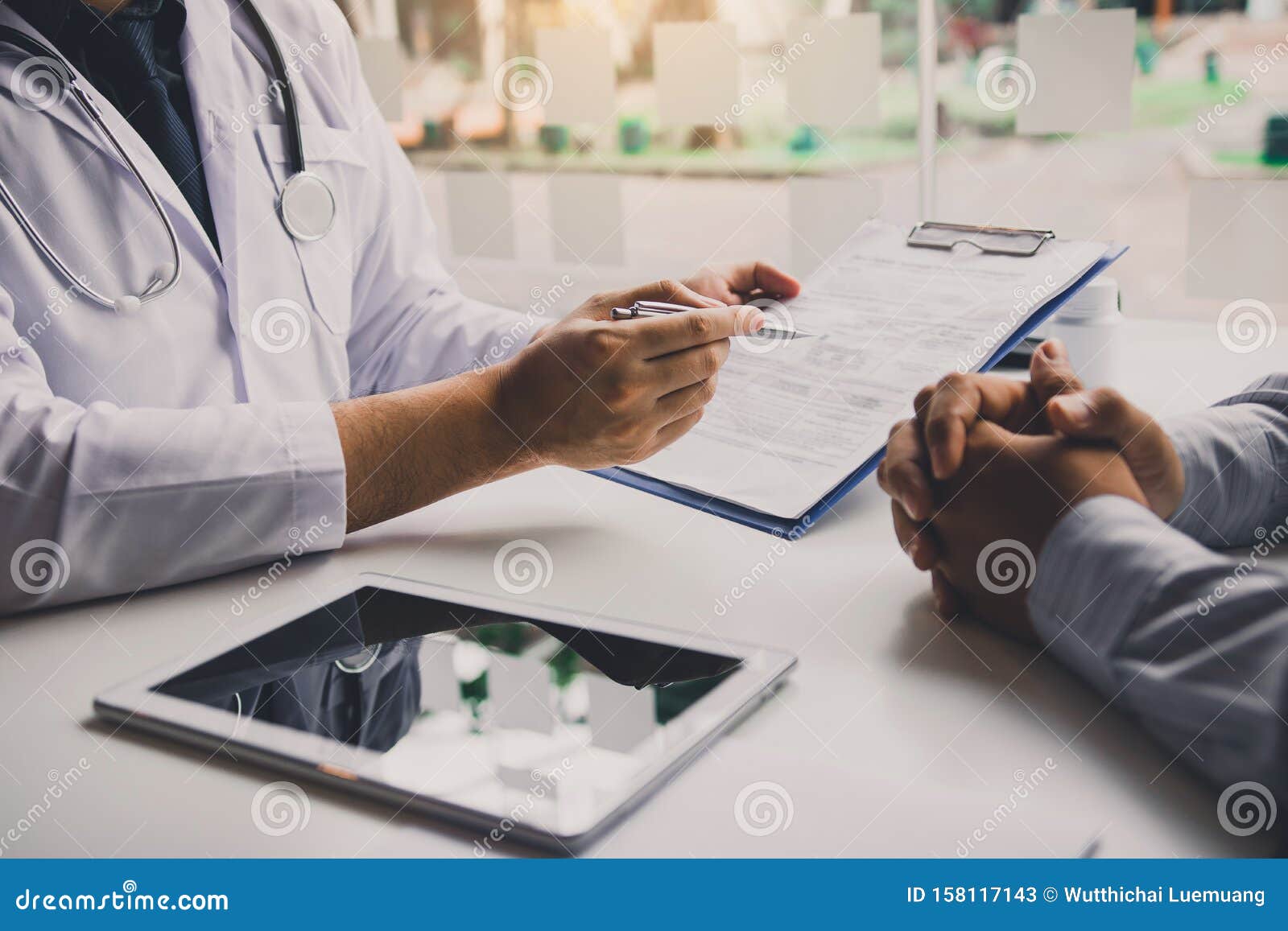 doctor is writing the appointment letter to the patient at the clinic