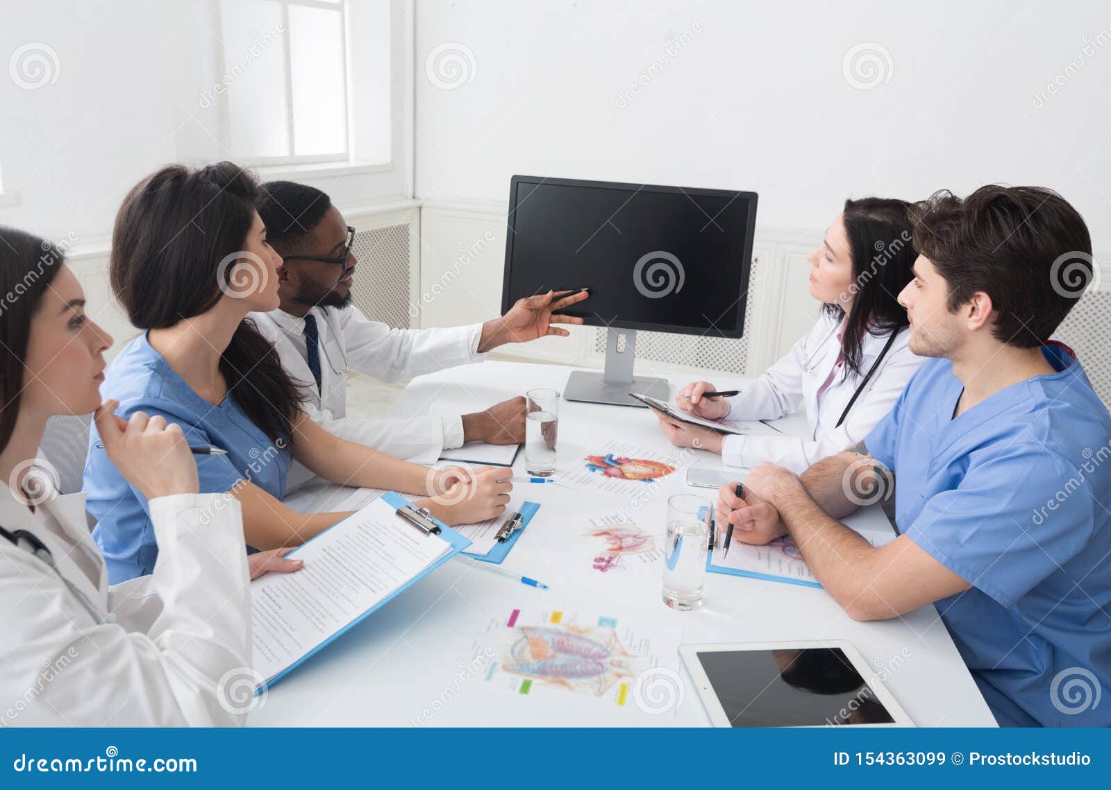 Doctors Having Lecture And Taking Notes In Meeting Room Stock