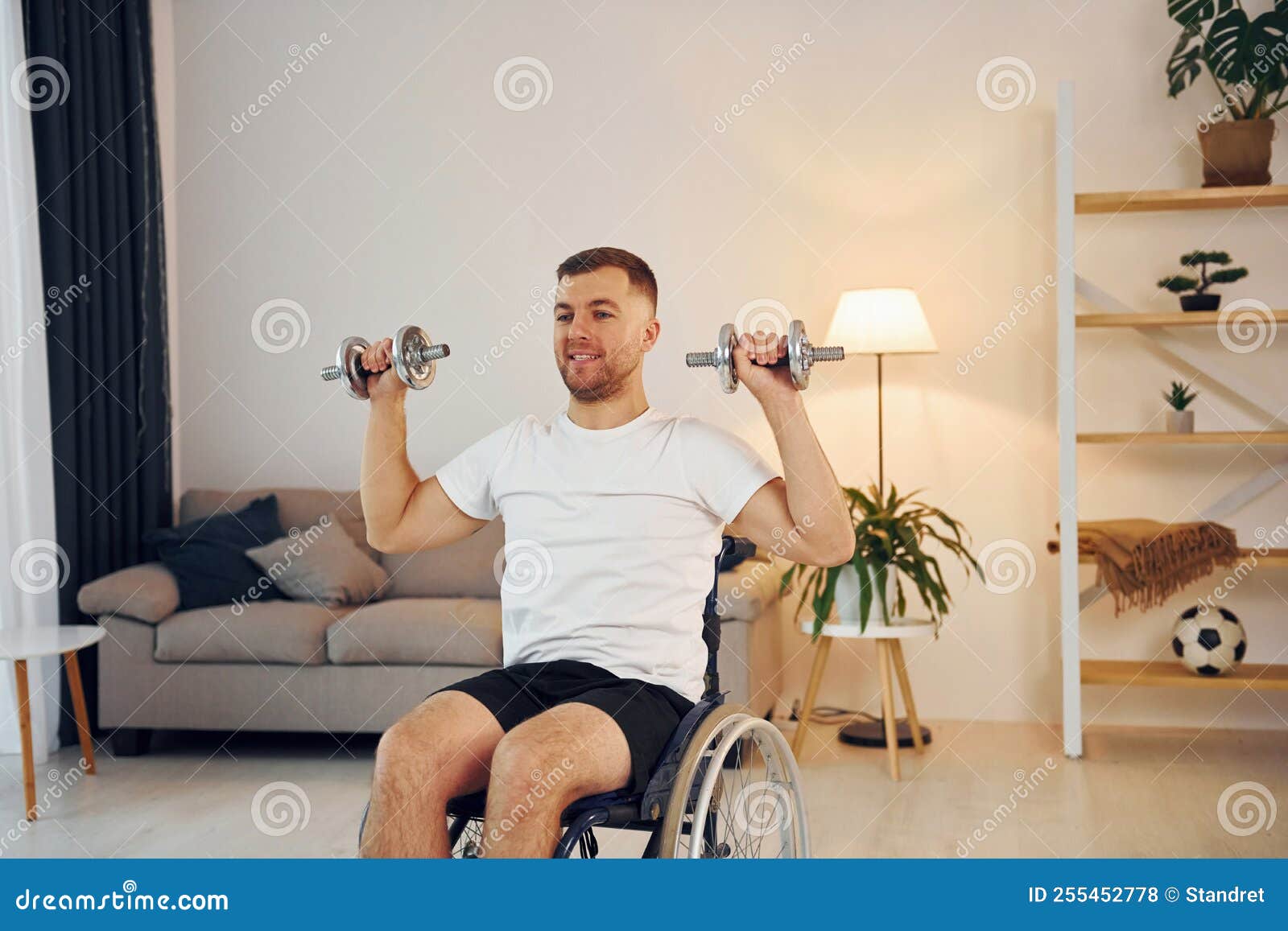 Doing Exercises by Using Dumbbells. Disabled Man in Wheelchair is at Home Stock Photo Image of