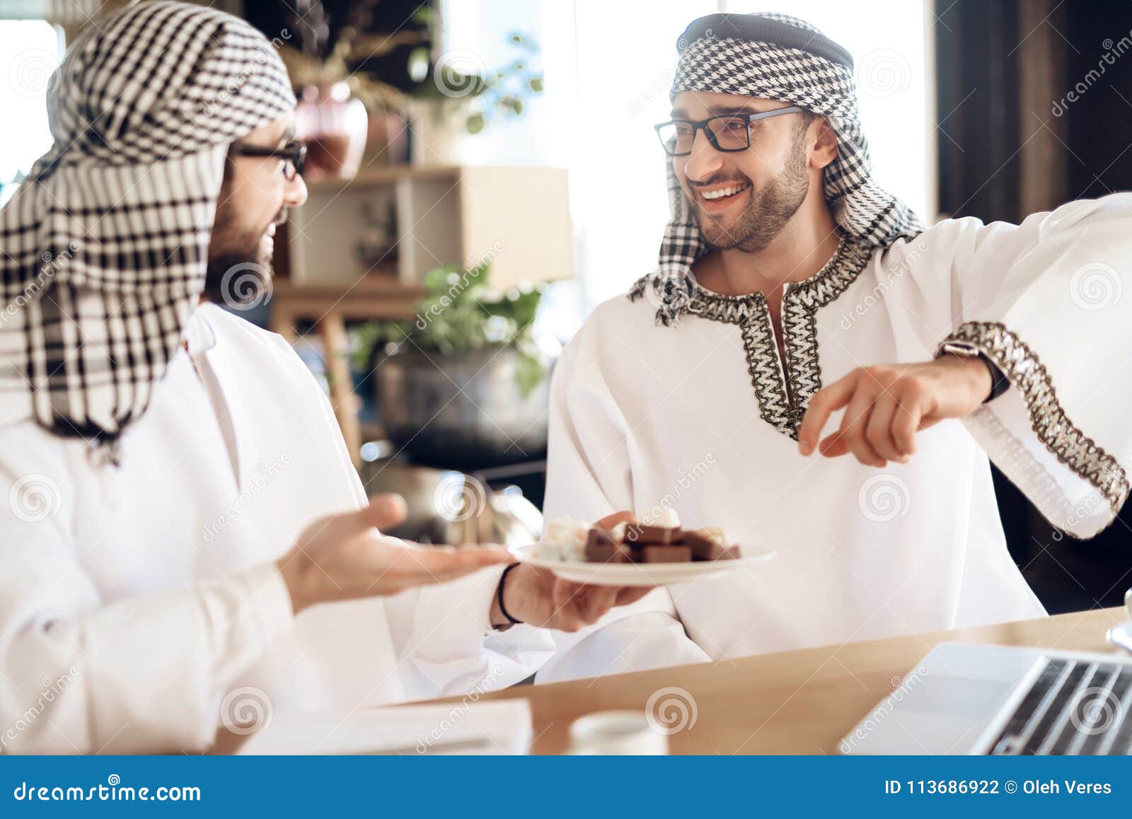 Dois homens de negócios árabes que jogam a xadrez na tabela na sala de hotel.