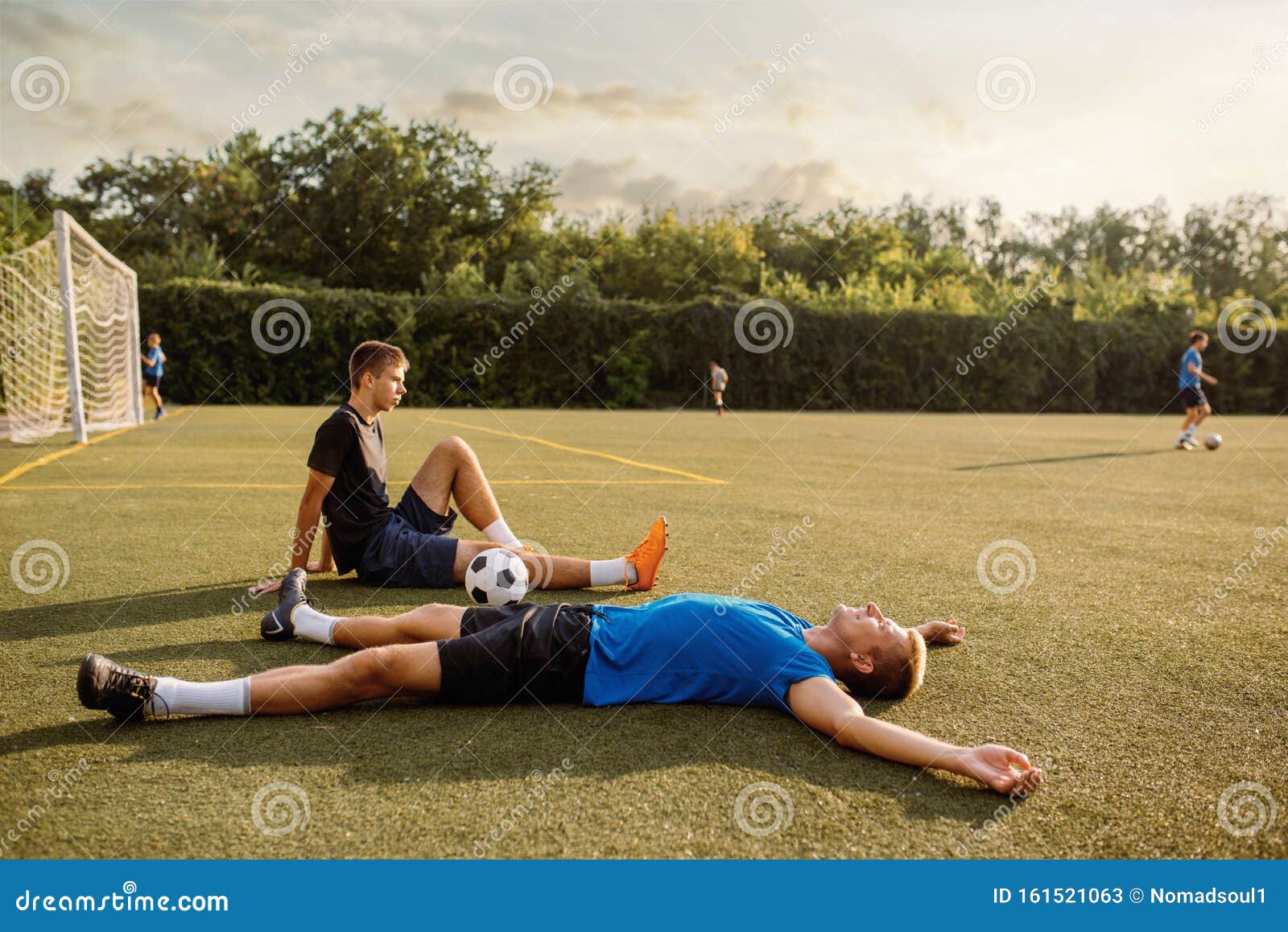 Dois jogadores de futebol masculinos deitado na grama do campo