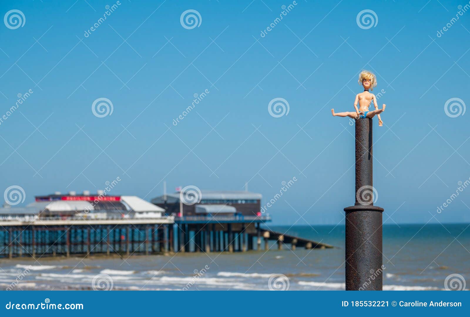 Doll Sitting on Top of a Tractor Chimney Exhaust, with Cromer Pier in