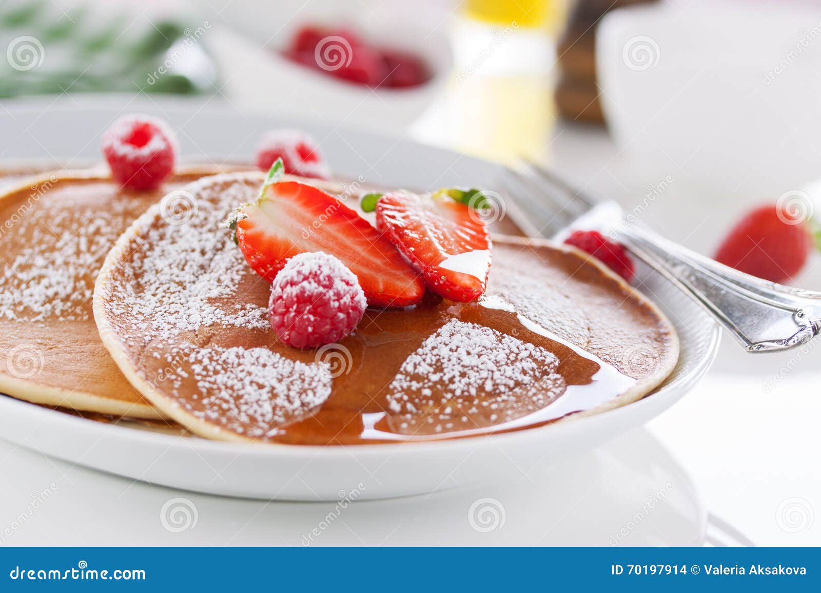 Domowej roboty maślanki amerykańscy bliny z świeżą truskawką i malinką na białym talerzu na białym stole dla śniadania, zbliżenie, selekcyjna ostrość