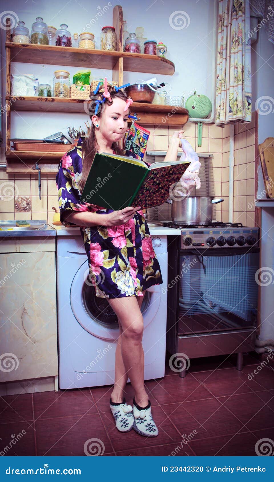 Dona de casa com livro e carcaça de uma galinha nas mãos. A dona de casa parva com livro e carcaça de uma galinha nas mãos