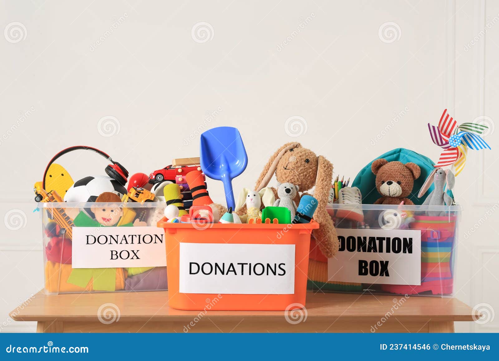 Donation Boxes with Different Child Toys on Wooden Table Stock Photo