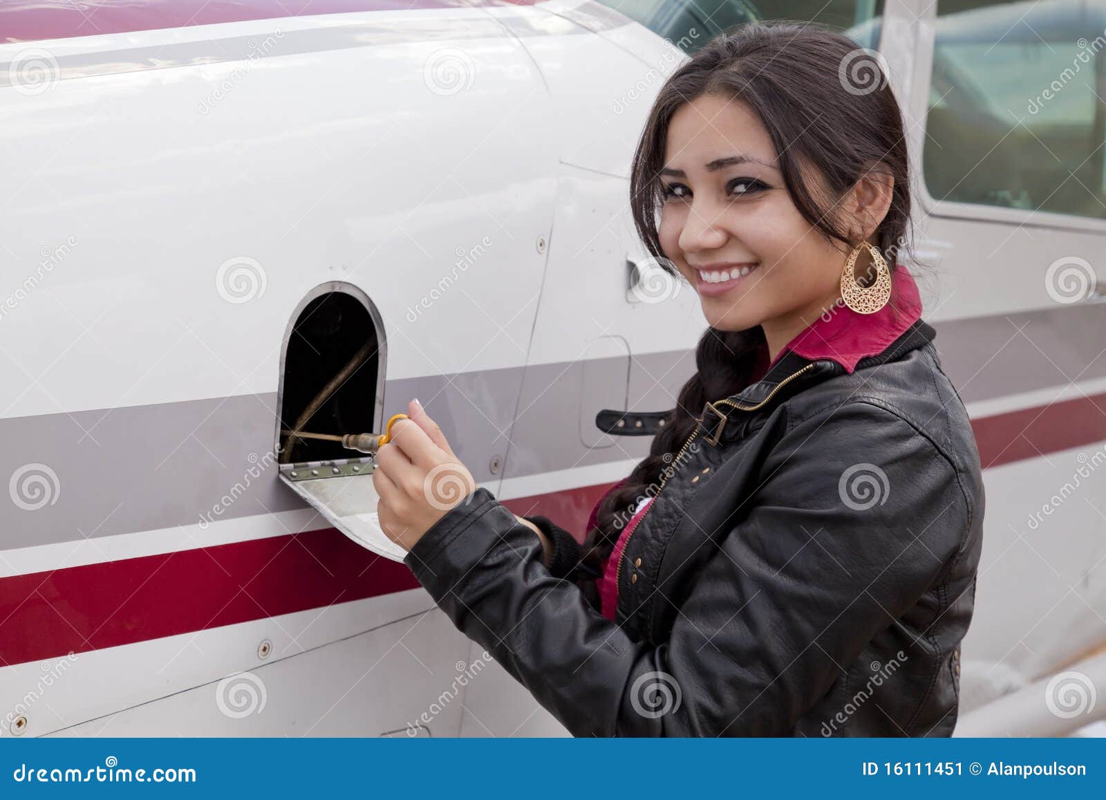 Donna che controlla olio in aeroplano. Una donna sta controllando l'olio in un aeroplano.