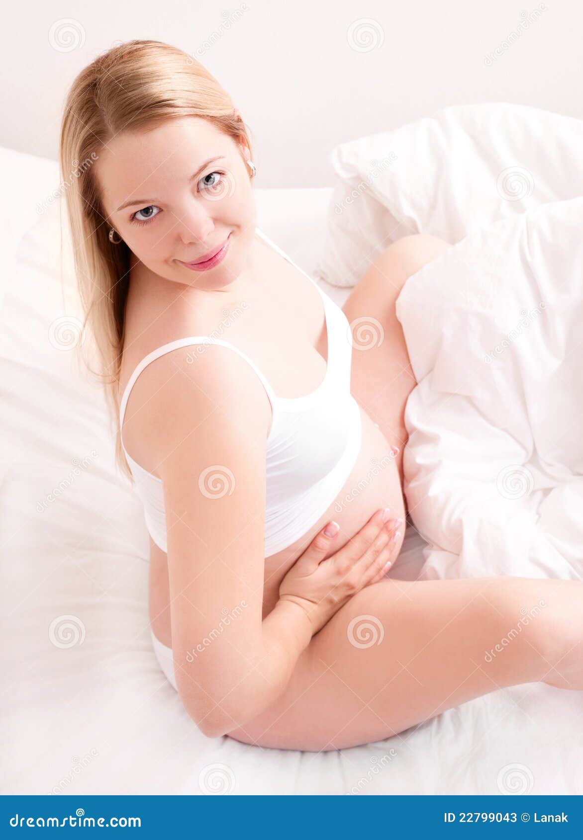 Bella giovane donna incinta che si siede nella base nel paese e che tocca la sua pancia