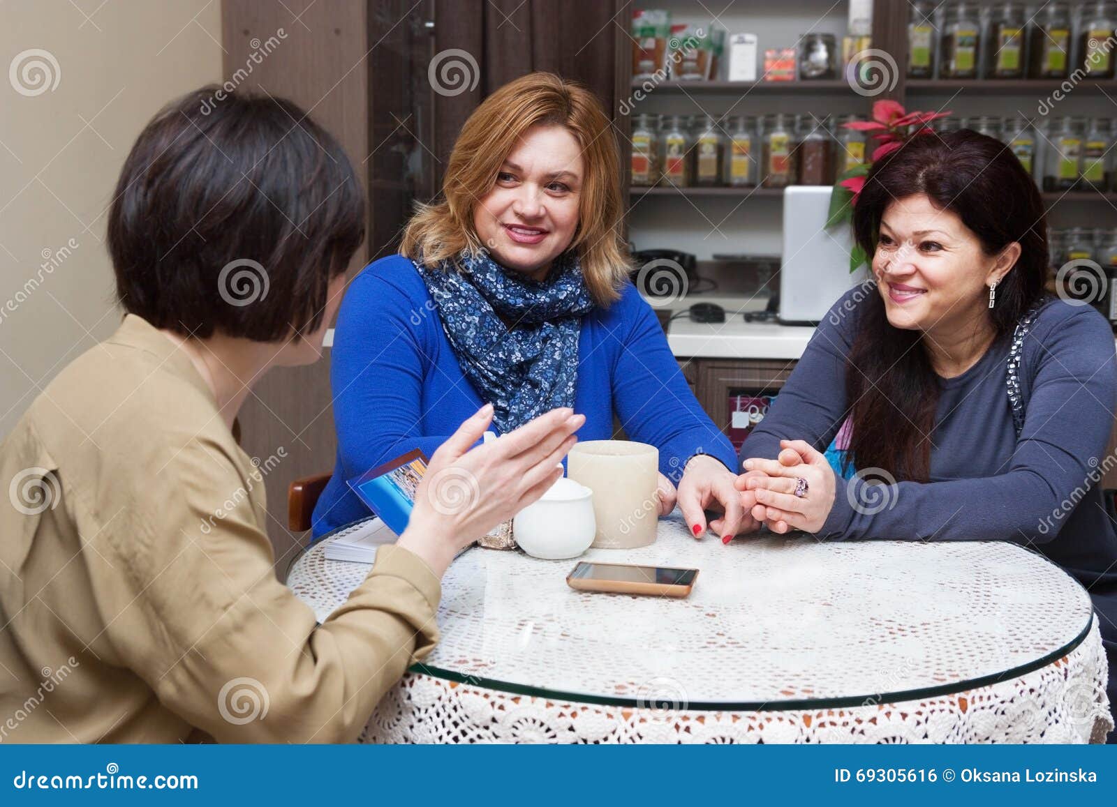 Donna matura in caffè. Tre amici adulti che parlano in retro caffè