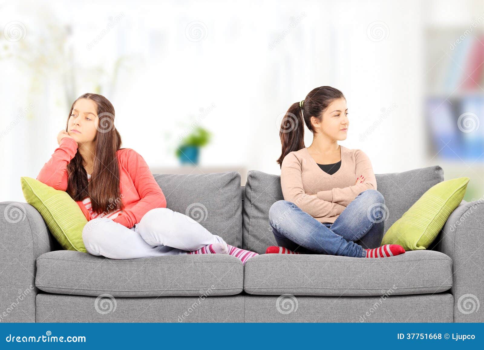 Dos adolescentes enojados que se sientan en el sofá, en casa,. Dos adolescentes que se sientan en el sofá, en casa, enojado con uno a